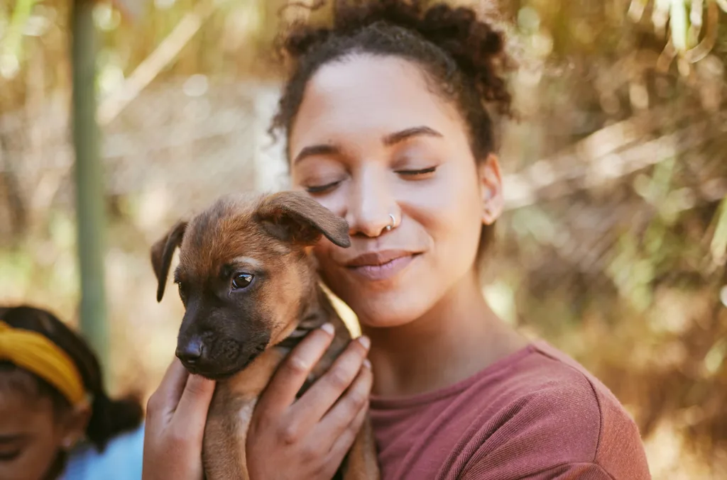 Mulher abraçando um filhote de cachorro no colo